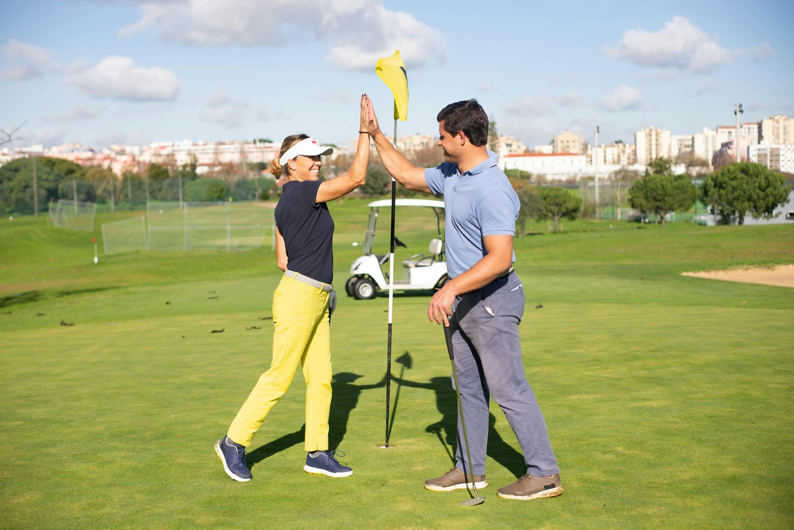 Two golfers high-fiving on the green at the DFC Charity Tournament.
